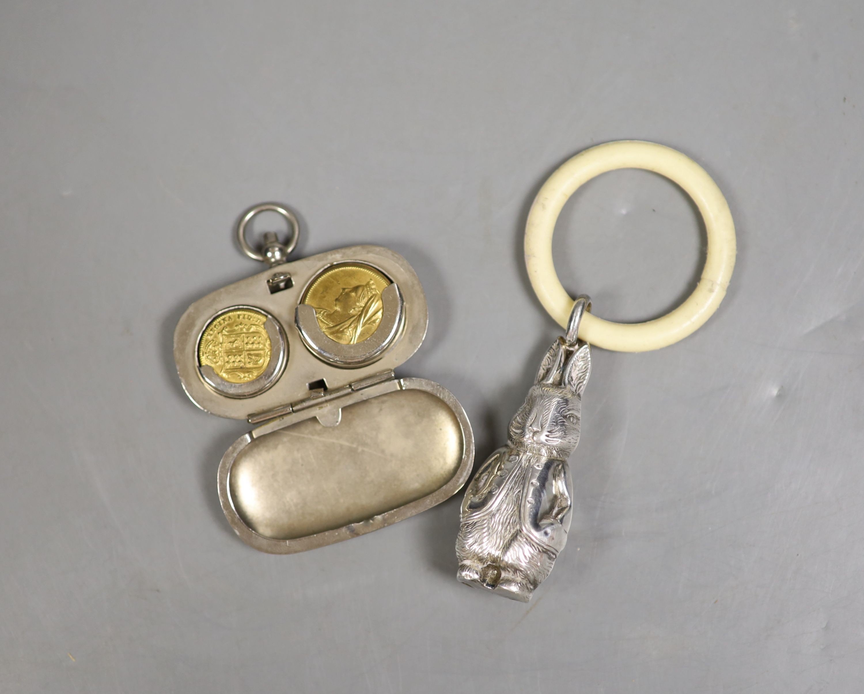 A silver plated sovereign case with faux sovereigns and a childs rattle.